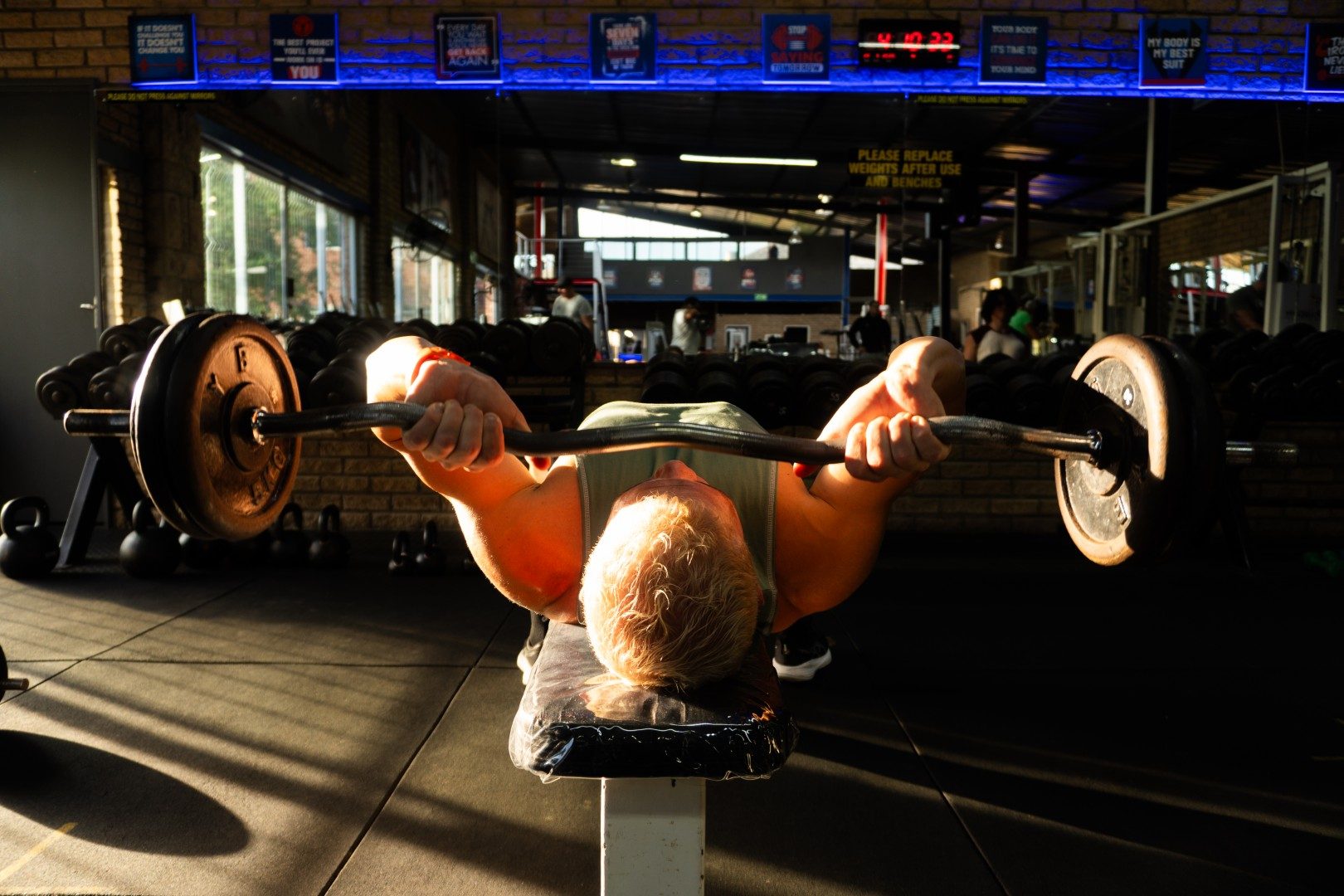 Older athlete performing barbell bench press at Oxigim
