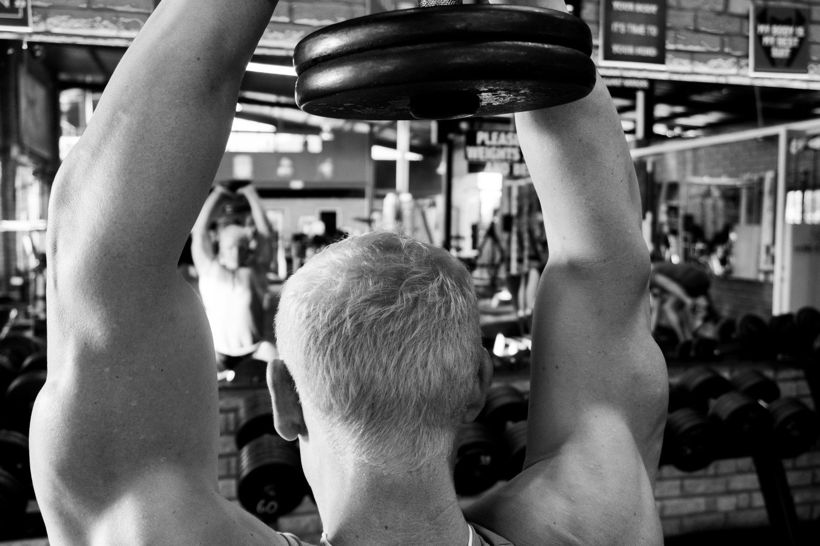 Gym member doing overhead dumbbell press
