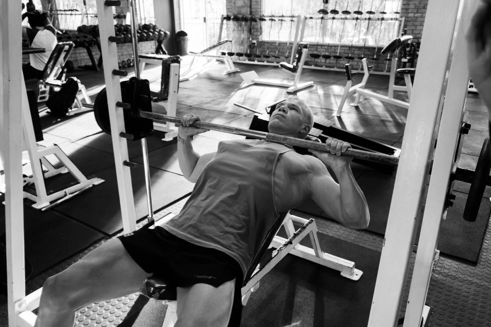 Gym member bench pressing in black and white