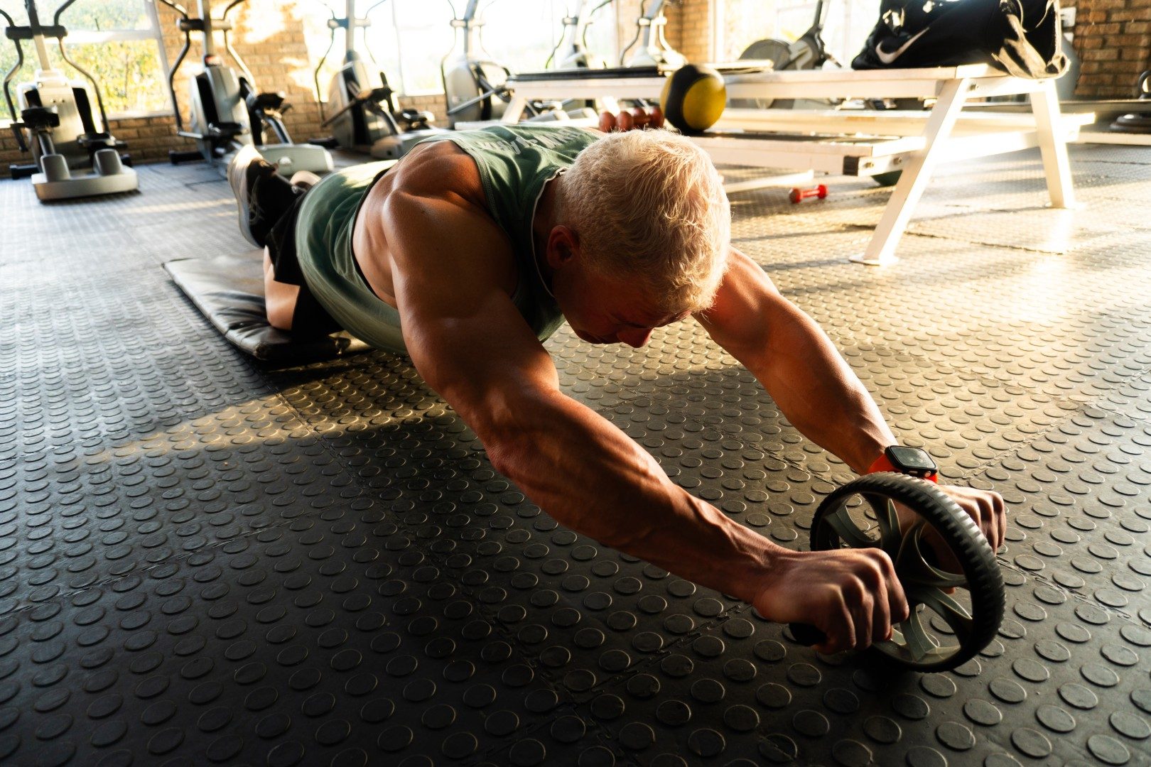Gym member extended on ab roller at Oxigim