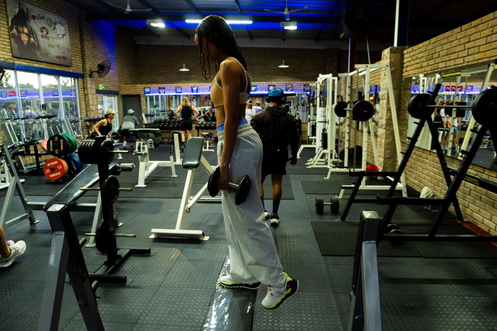 Female member carrying dumbbells across Oxigim gym floor