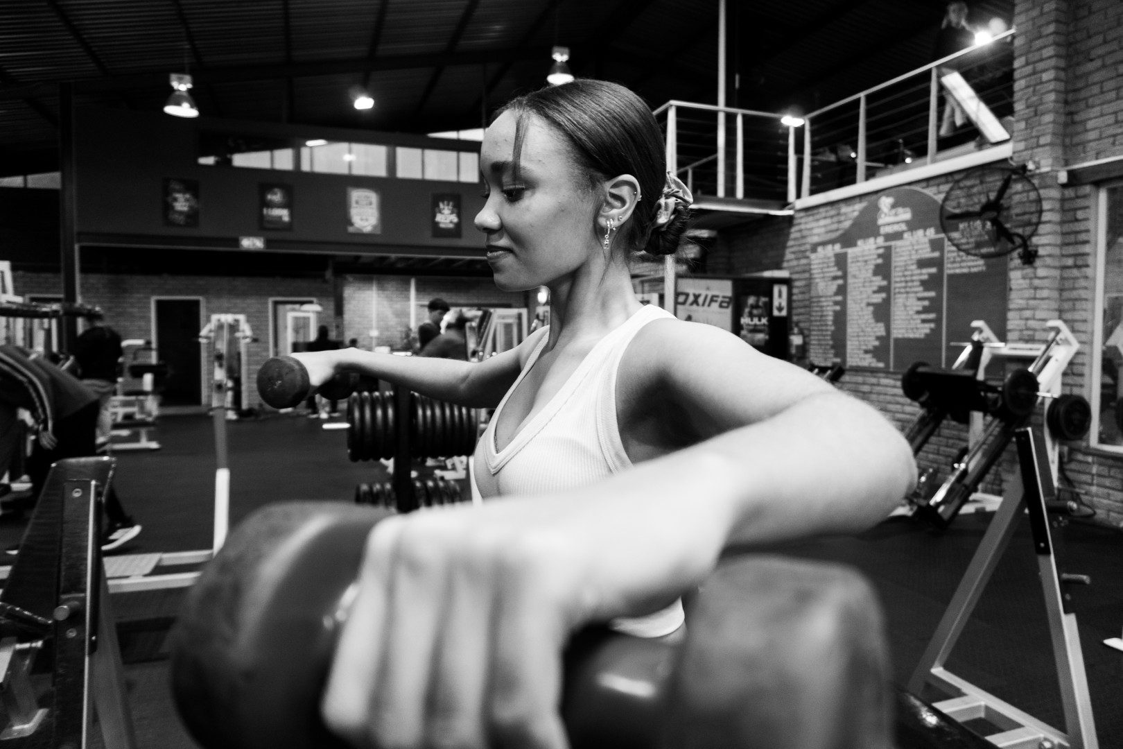 Female gym member doing lunge with dumbbells at Oxigim
