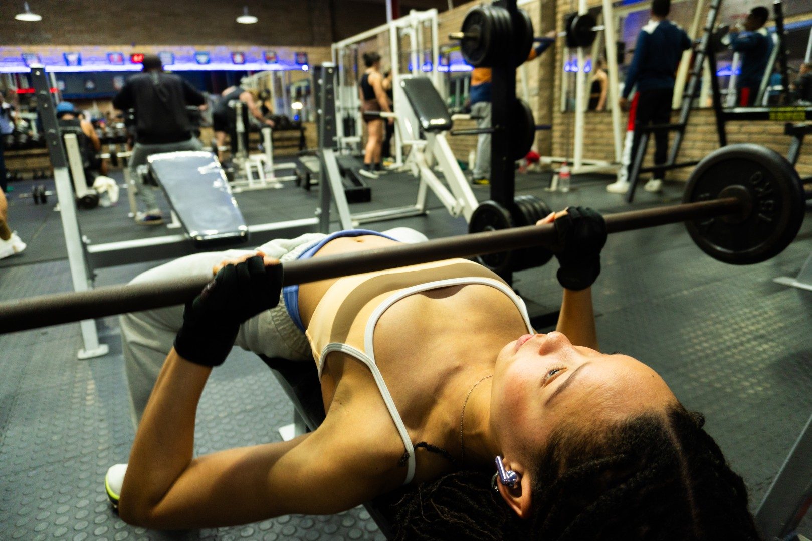 Female member performing barbell bench press