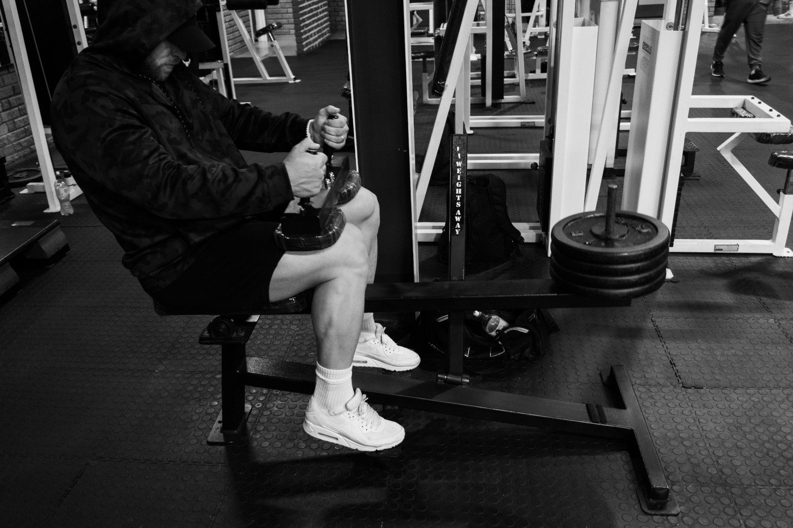 Gym member doing seated row exercise in black and white